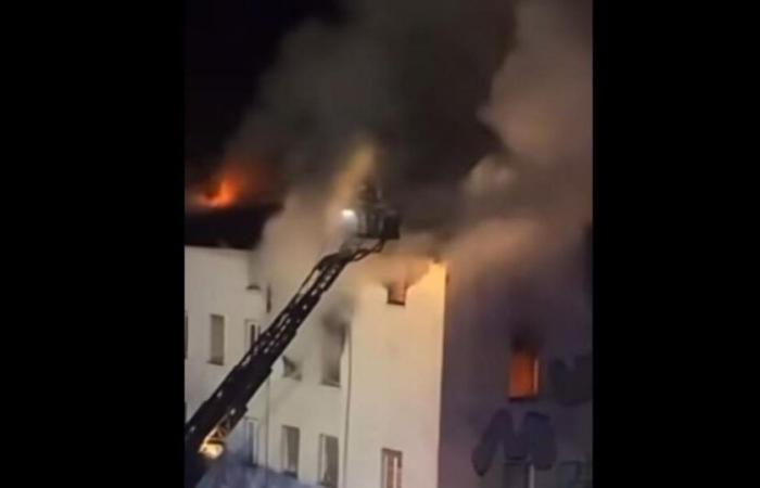 deux personnes se défendent depuis une fenêtre pour échapper à un squat en feu connu pour son délabrement